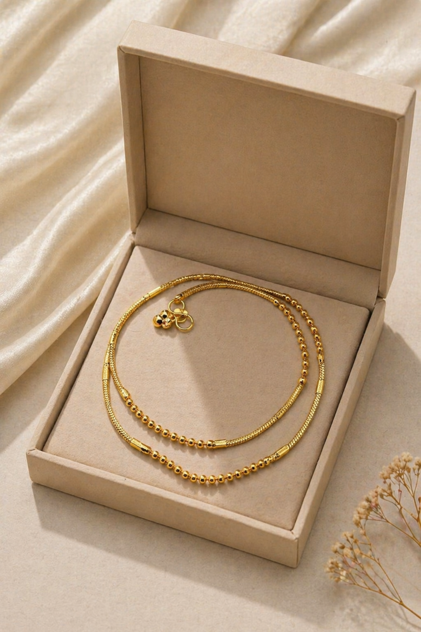 Gold necklace in an open beige jewelry box on a soft beige fabric background