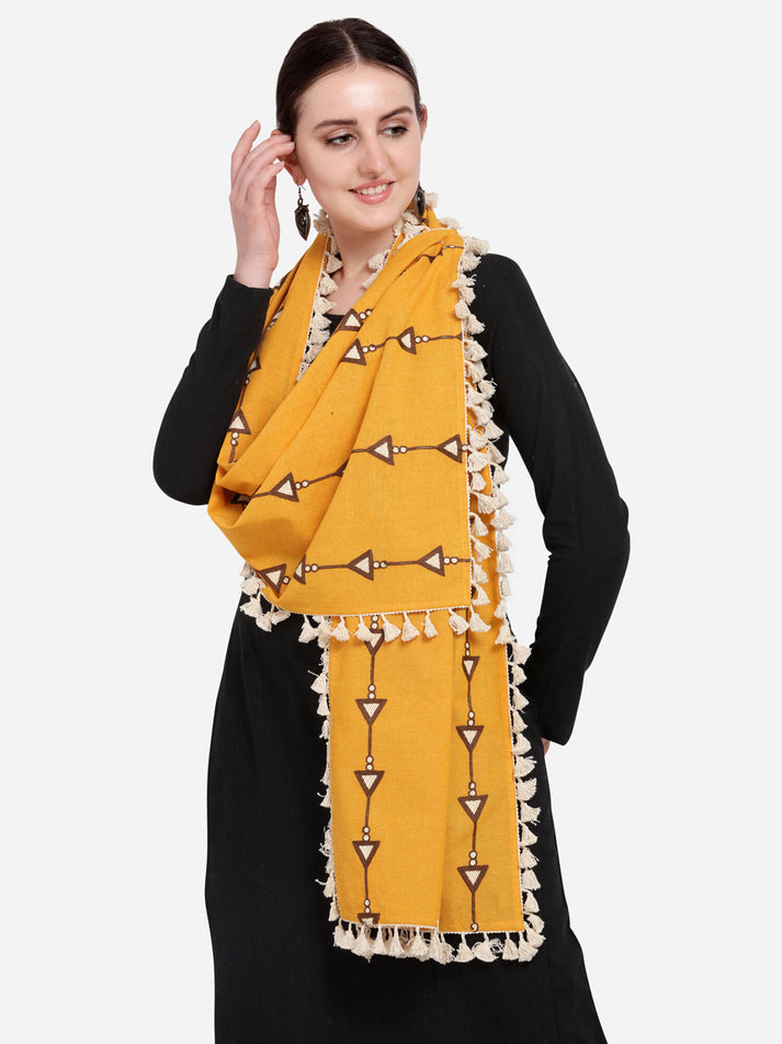 Woman wearing a mustard yellow scarf with decorative patterns on a plain background