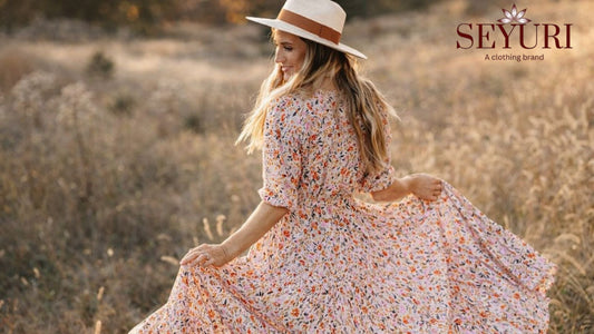 Woman wearing a flowy floral maxi dress in a field, showcasing spring 2026 fashion trends with soft pastel colors and feminine silhouette