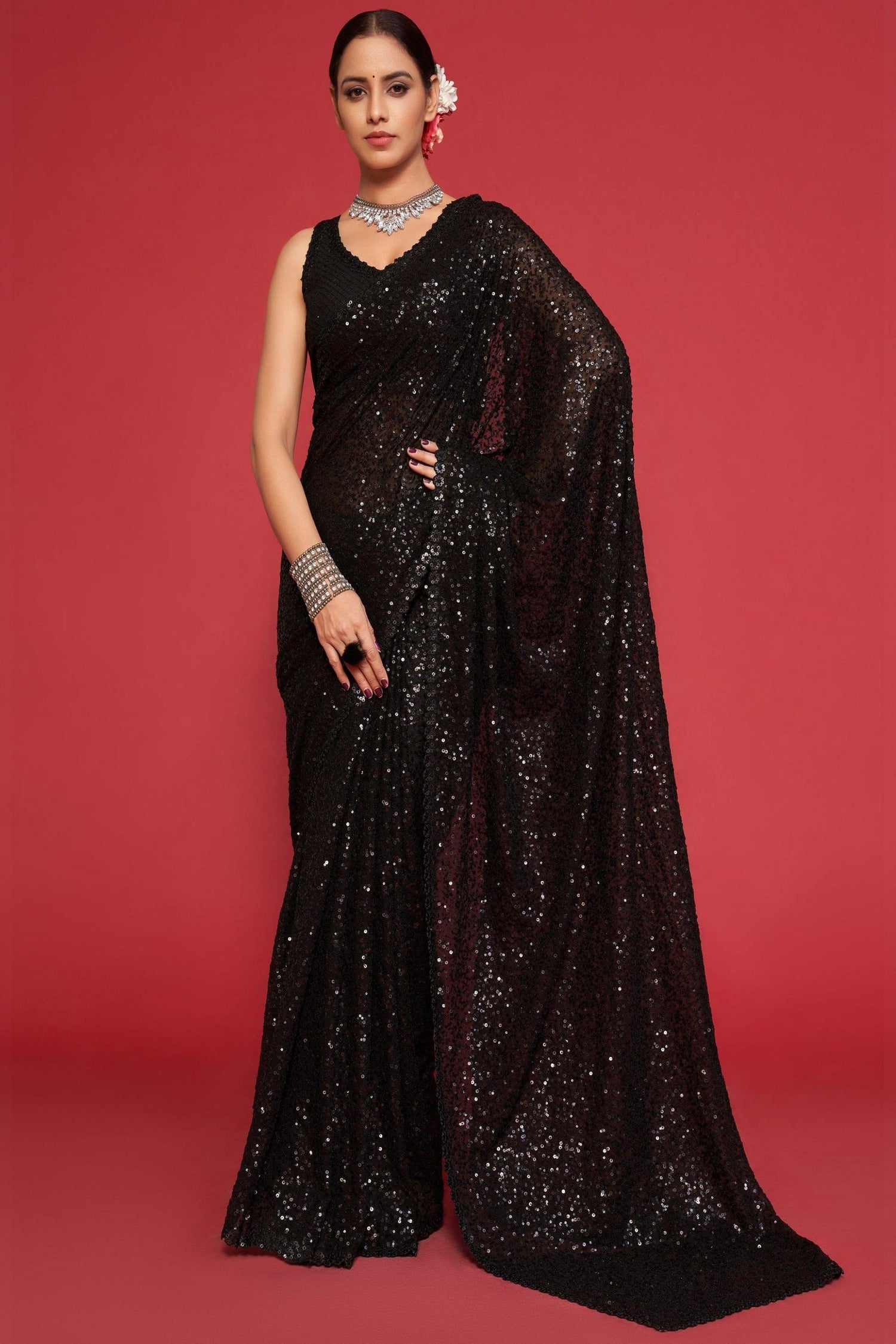 Woman wearing a black sequin saree against a red background