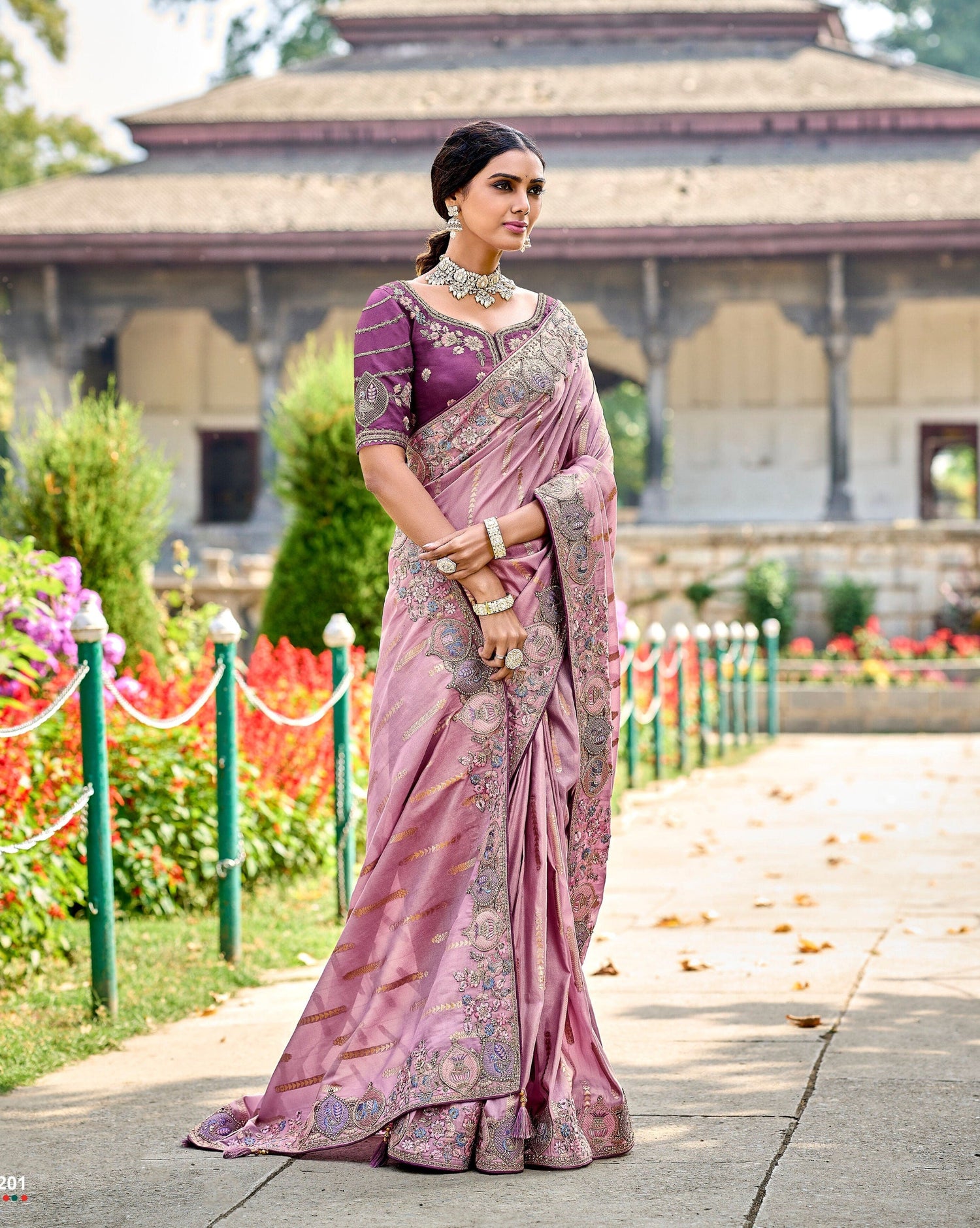 Woman in a traditional saree with a garden and building in the background
