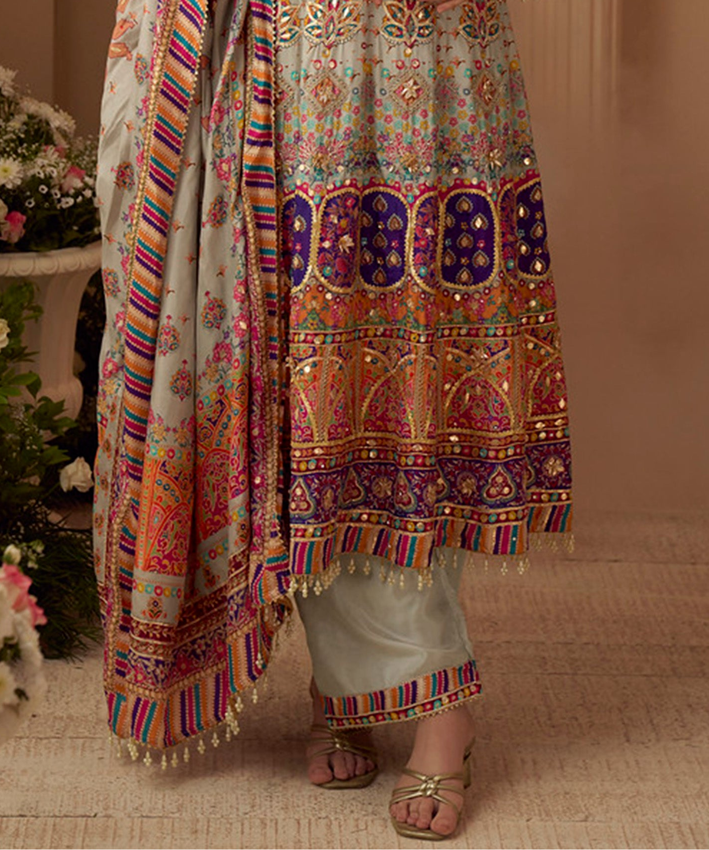 Traditional embroidered outfit with colorful patterns on a neutral background
