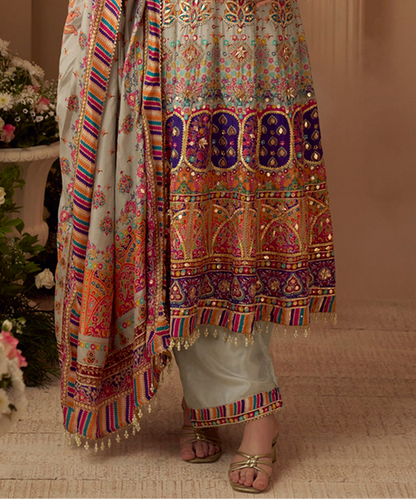 Traditional embroidered outfit with colorful patterns on a neutral background
