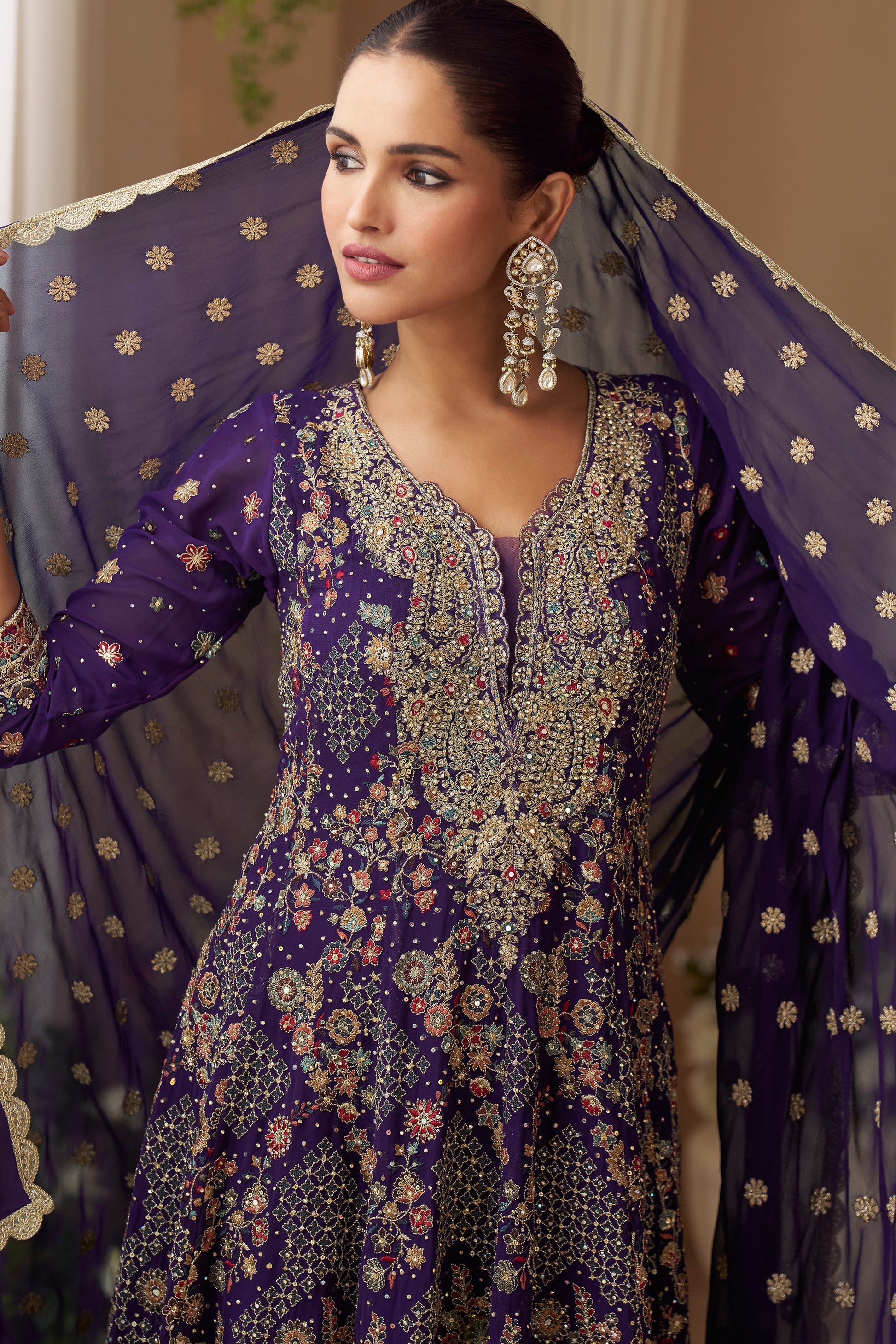Woman in a purple embroidered traditional outfit with a sheer dupatta.