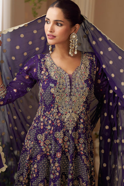 Woman in a purple embroidered traditional outfit with a sheer dupatta.