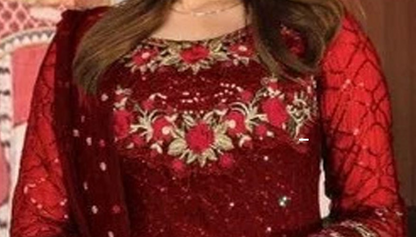 A close-up of a red embroidered traditional outfit with floral embroidery and sequins, worn by a model.