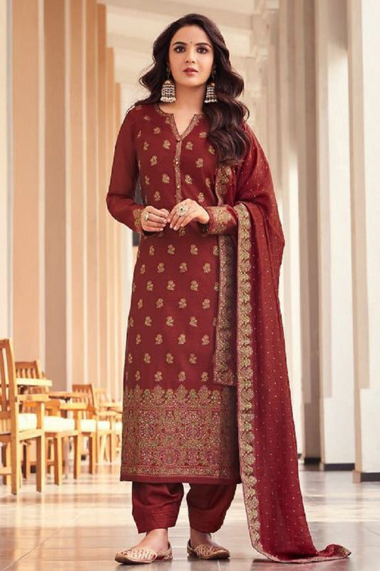 Woman in a red traditional outfit with gold patterns in an indoor setting.