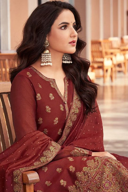 Woman in a red traditional outfit with gold patterns in an indoor setting.