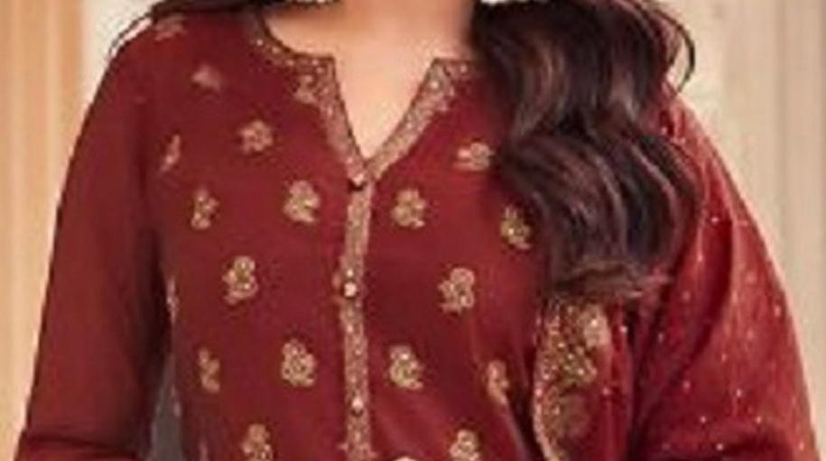 Woman in a red traditional outfit with gold patterns in an indoor setting.
