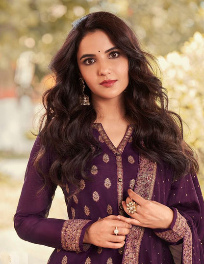 Woman wearing a purple traditional outfit with gold patterns outdoors.