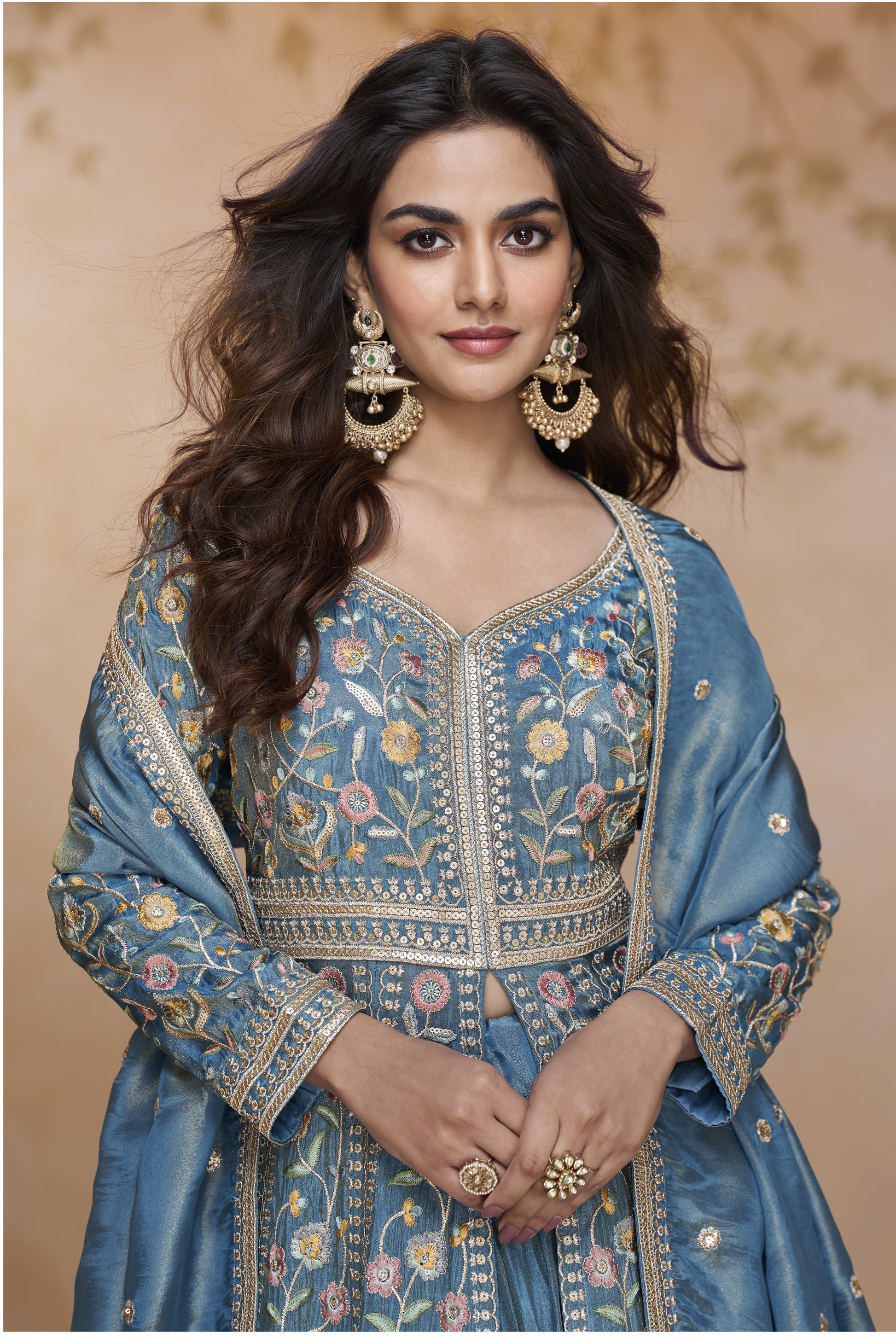 Blue Embroidered Floor-Length Gown with Detailed Floral Work, Long Sleeves, and Matching Dupatta Worn by a Woman at a Royal Backdrop.