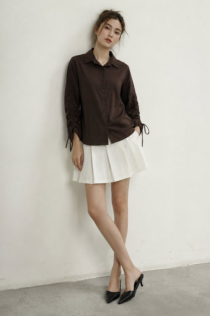 Brown shirt displaying gathered sleeves and tie details