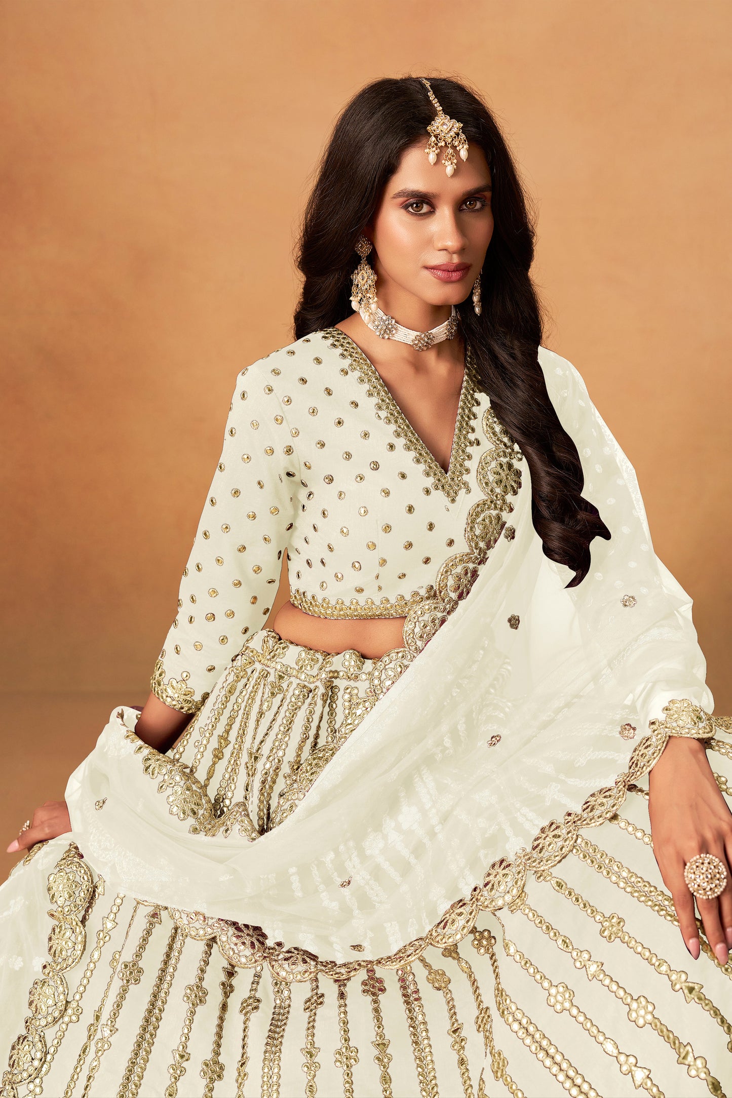 close view of heavy embroidery work on off-white lehenga choli