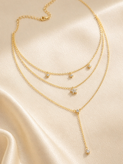 Gold necklace with diamond pendants on a beige fabric background