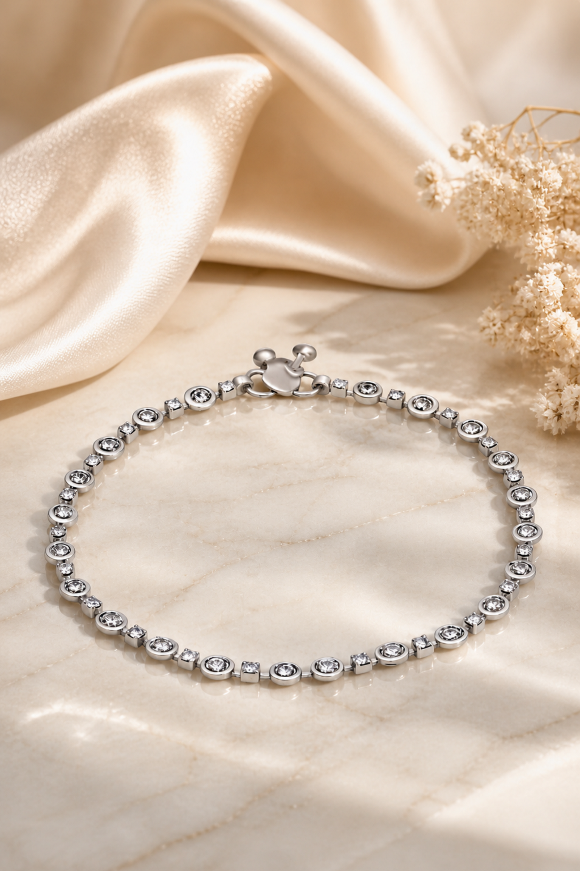 delicate silver anklet arranged in soft lighting with fabric backdrop
