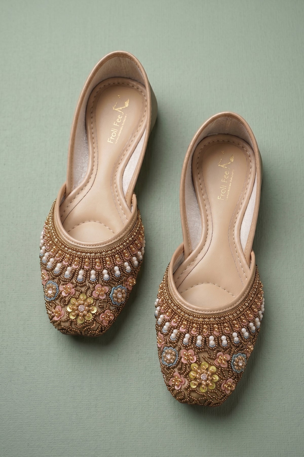 Pair of traditional gold footwear adorned with pink and yellow floral motifs