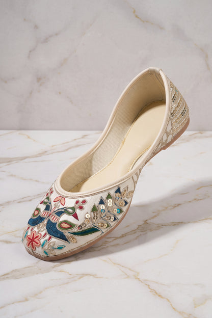 Angled view of off-white ethnic mojari showing side gold sequin vine accents