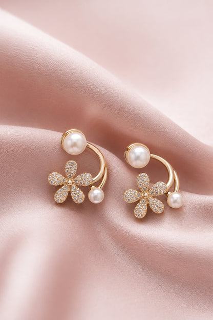 Floral earrings with clear stones and white pearl-like beads on blush fabric