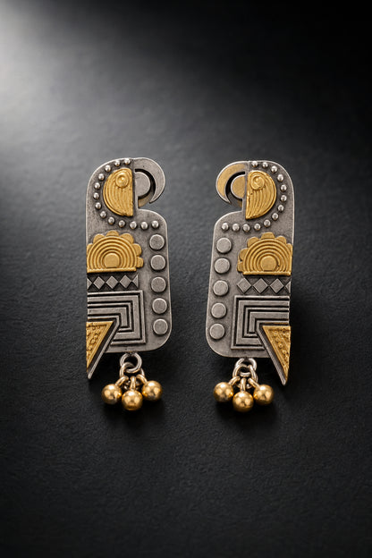 Mixed silver-tone and gold-tone geometric drop earrings on charcoal
