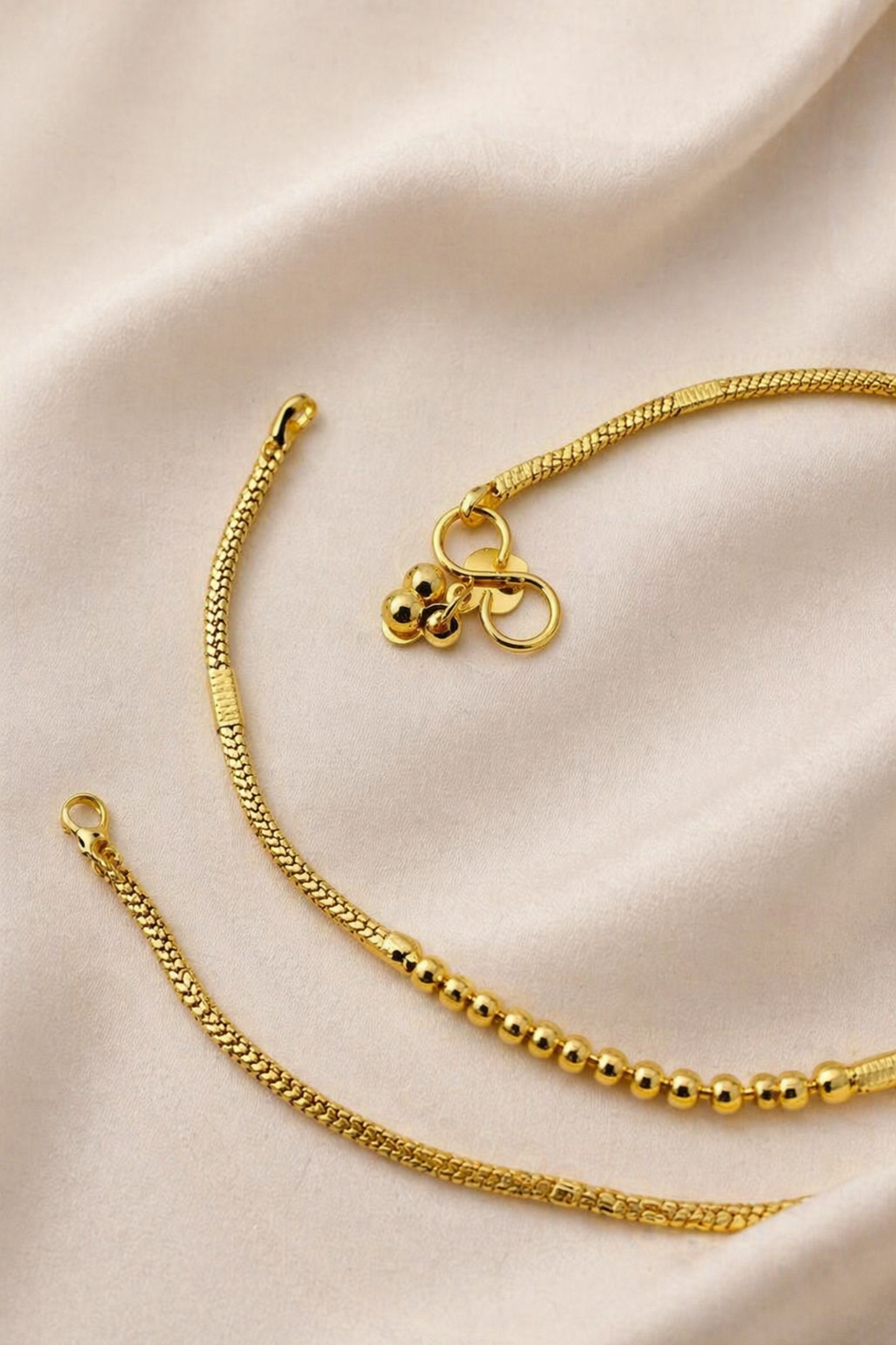 Gold bracelet with a bow charm on a beige satin background