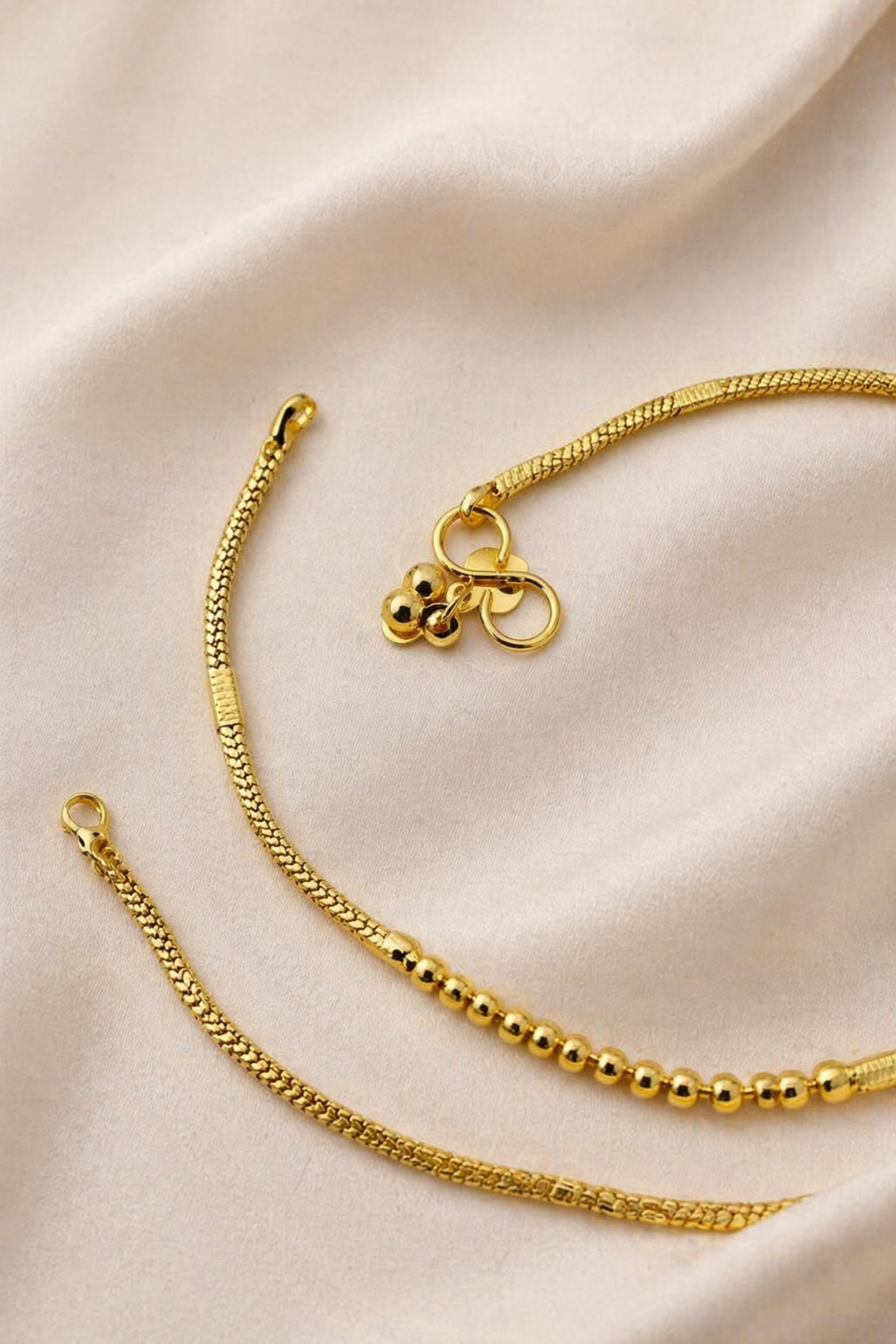 Gold bracelet with a bow charm on a beige satin background