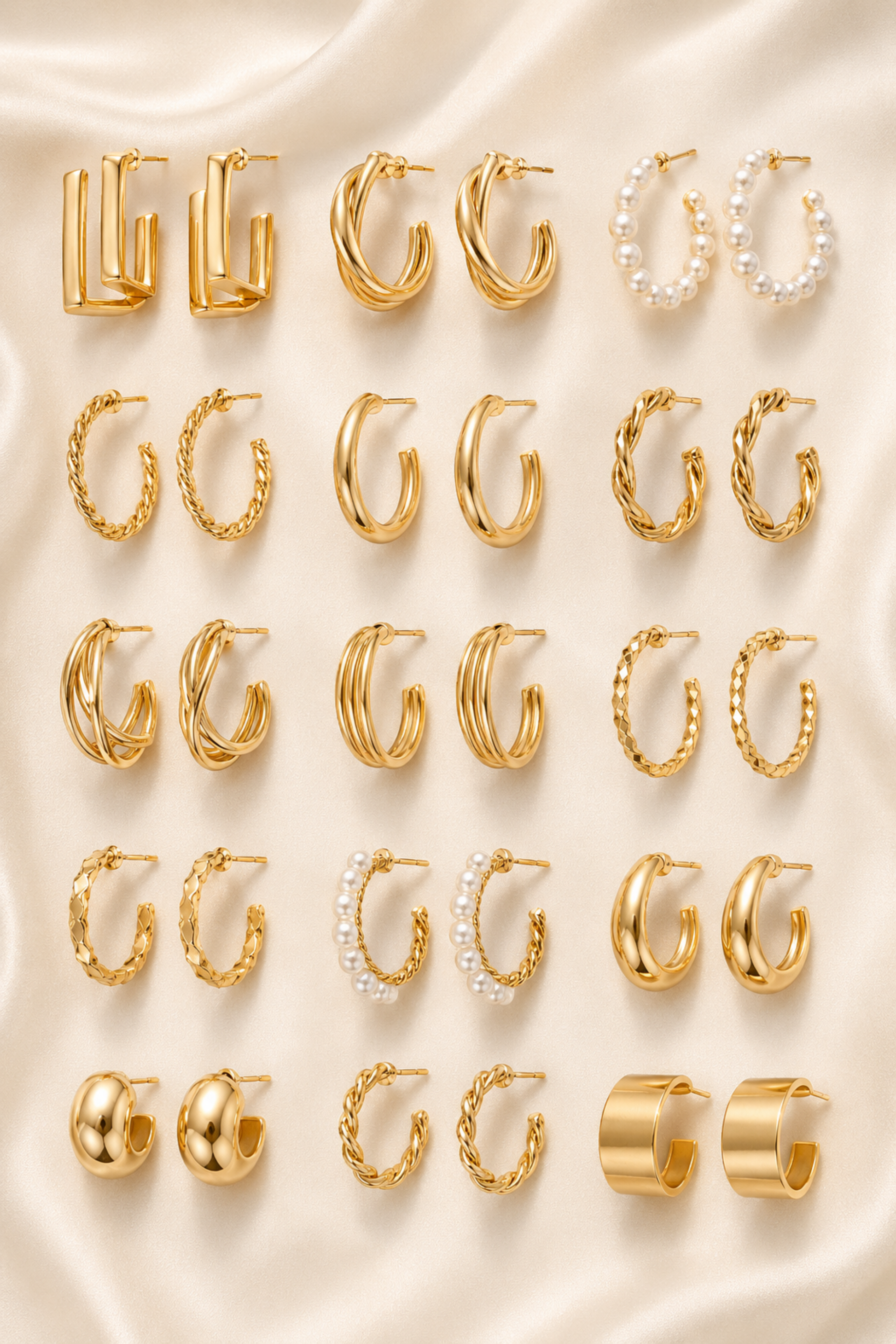 Eighteen gold-tone hoop earring designs arranged in rows on ivory satin