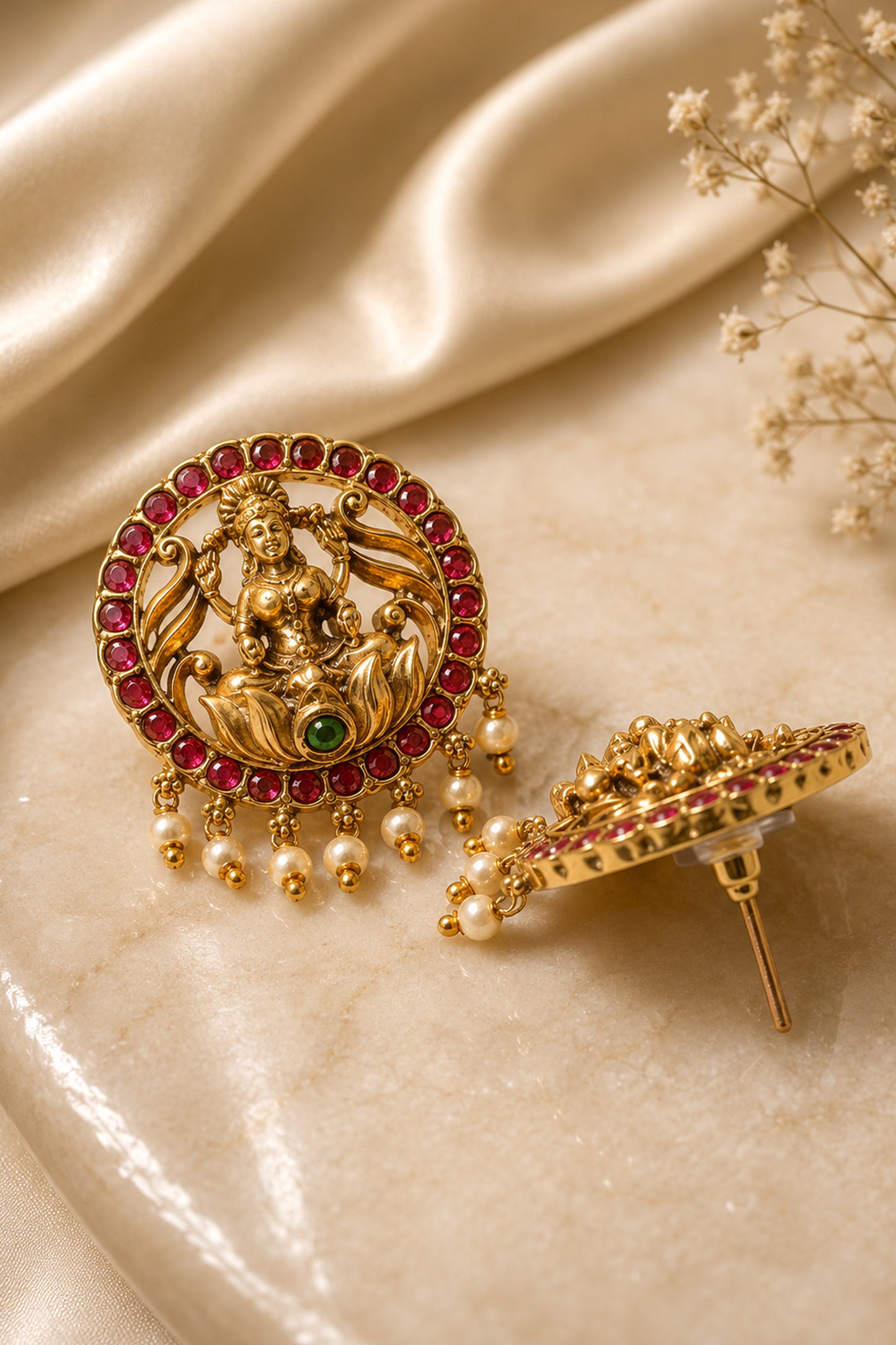 Matching circular earrings with polished sculpted surfaces, red stones and suspended pearl-like beads