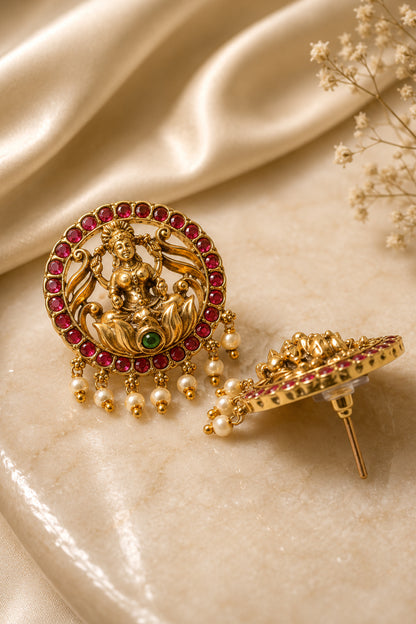 Matching circular earrings with polished sculpted surfaces, red stones and suspended pearl-like beads