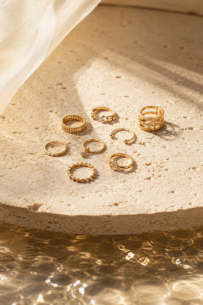 Gold tone ring set arranged on a warm stone surface