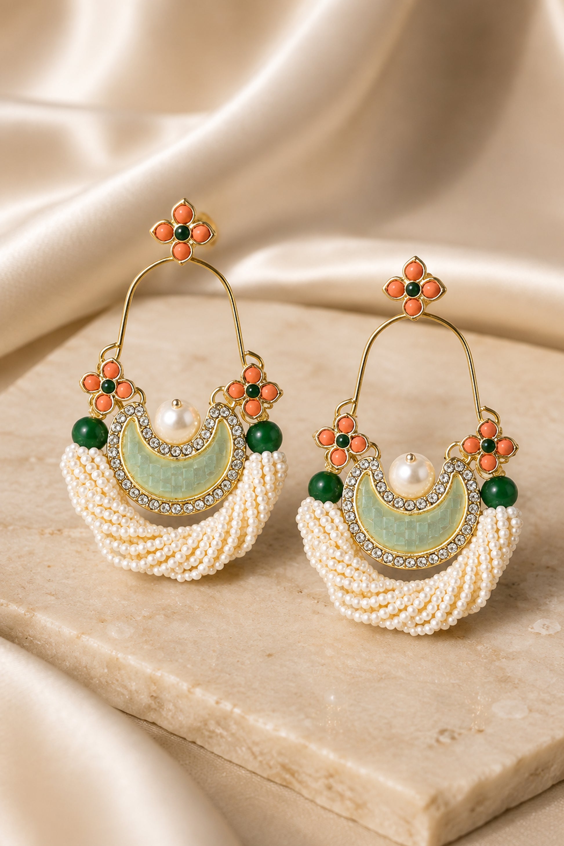 Pair of sculpted hoop earrings displayed on a neutral stone surface