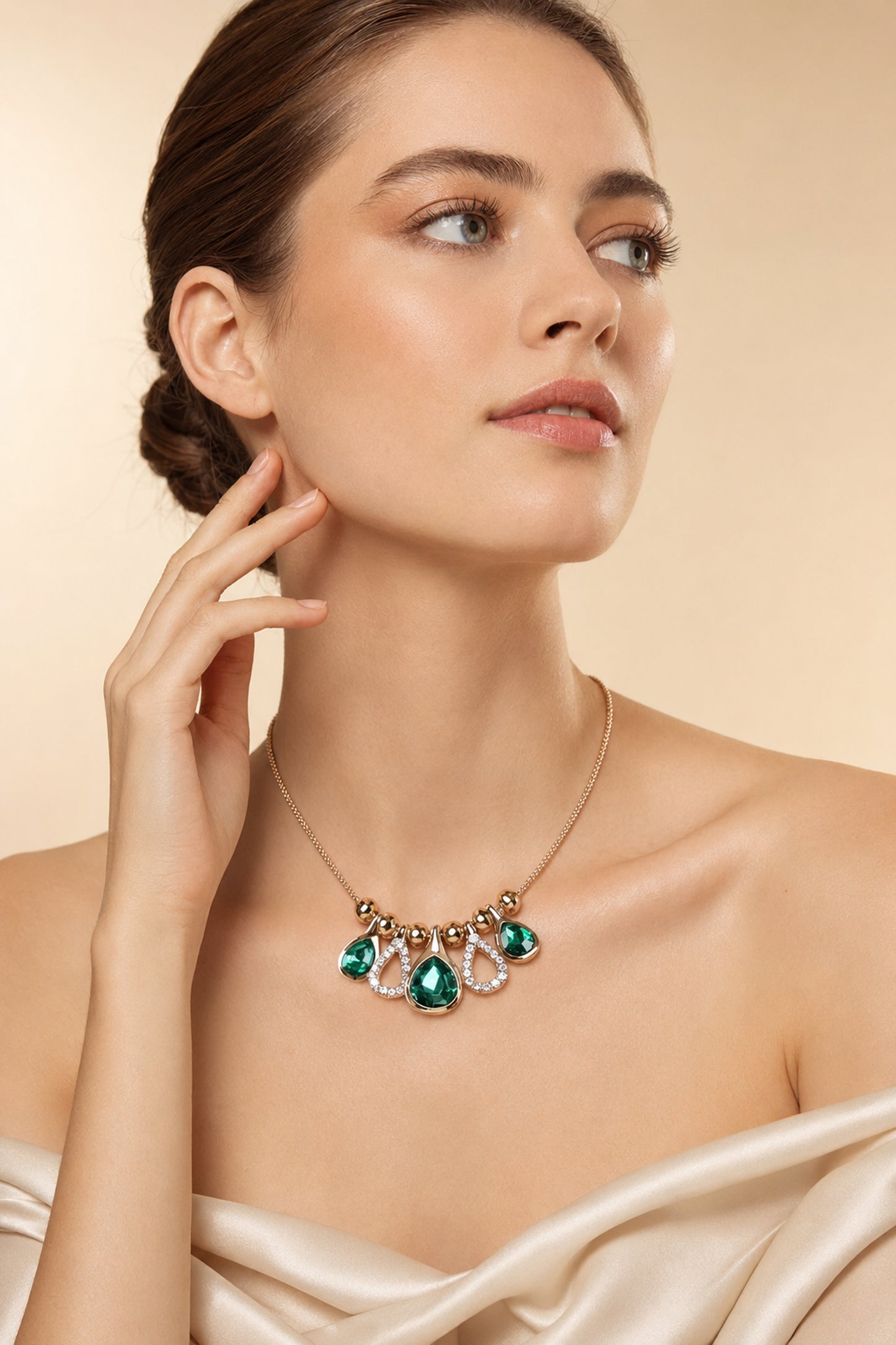 Teardrop necklace arranged against deep green fabric