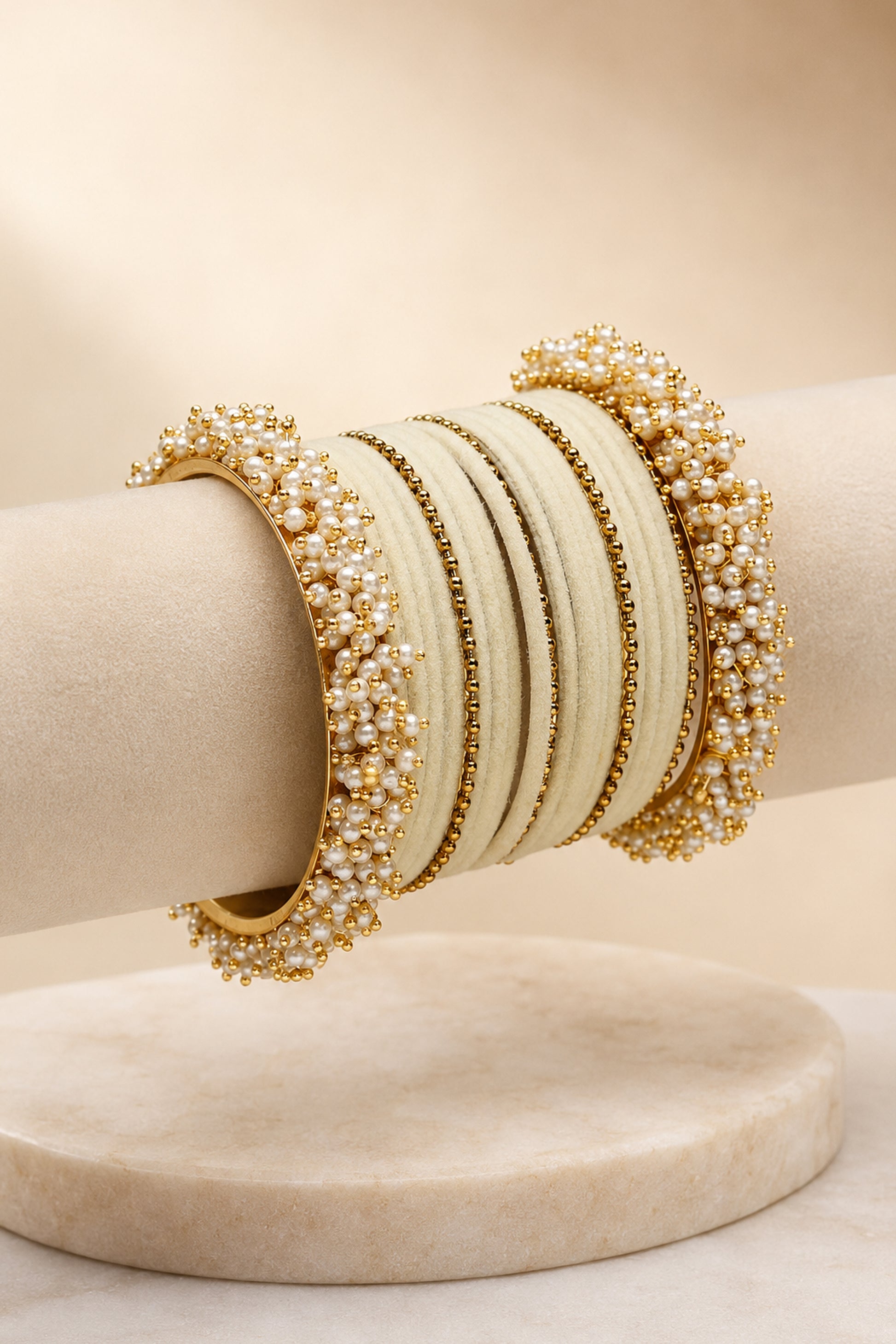 Ivory and gold-tone bangles displayed on cream marble