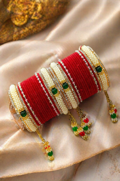 close-up of red thread bangles with cream beads and green stones