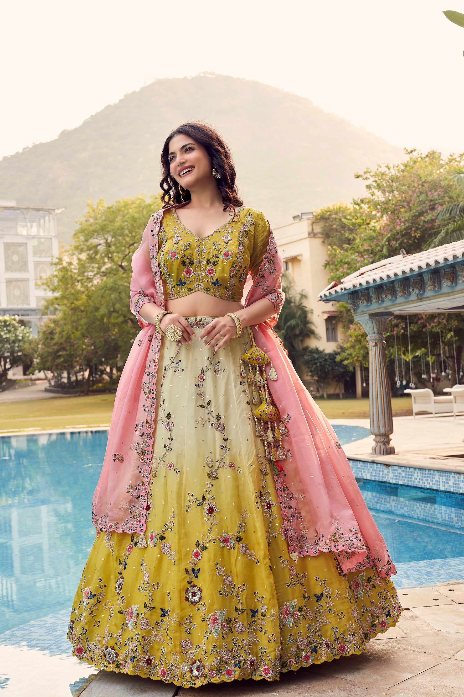 Woman Dressed in a Floral Designer Lehenga Set, posing in a royal with Background.