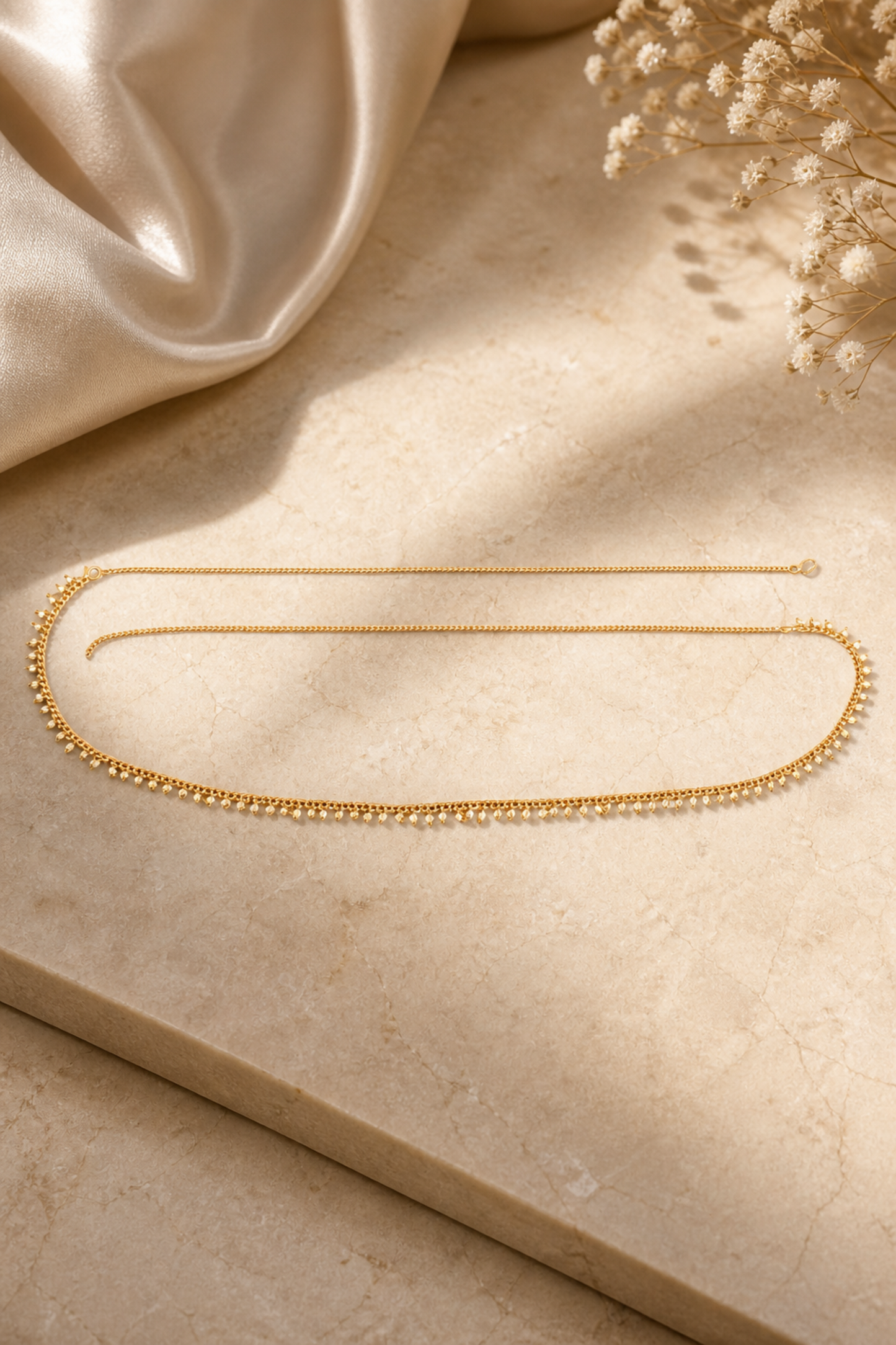 minimal gold waist chain on neutral surface