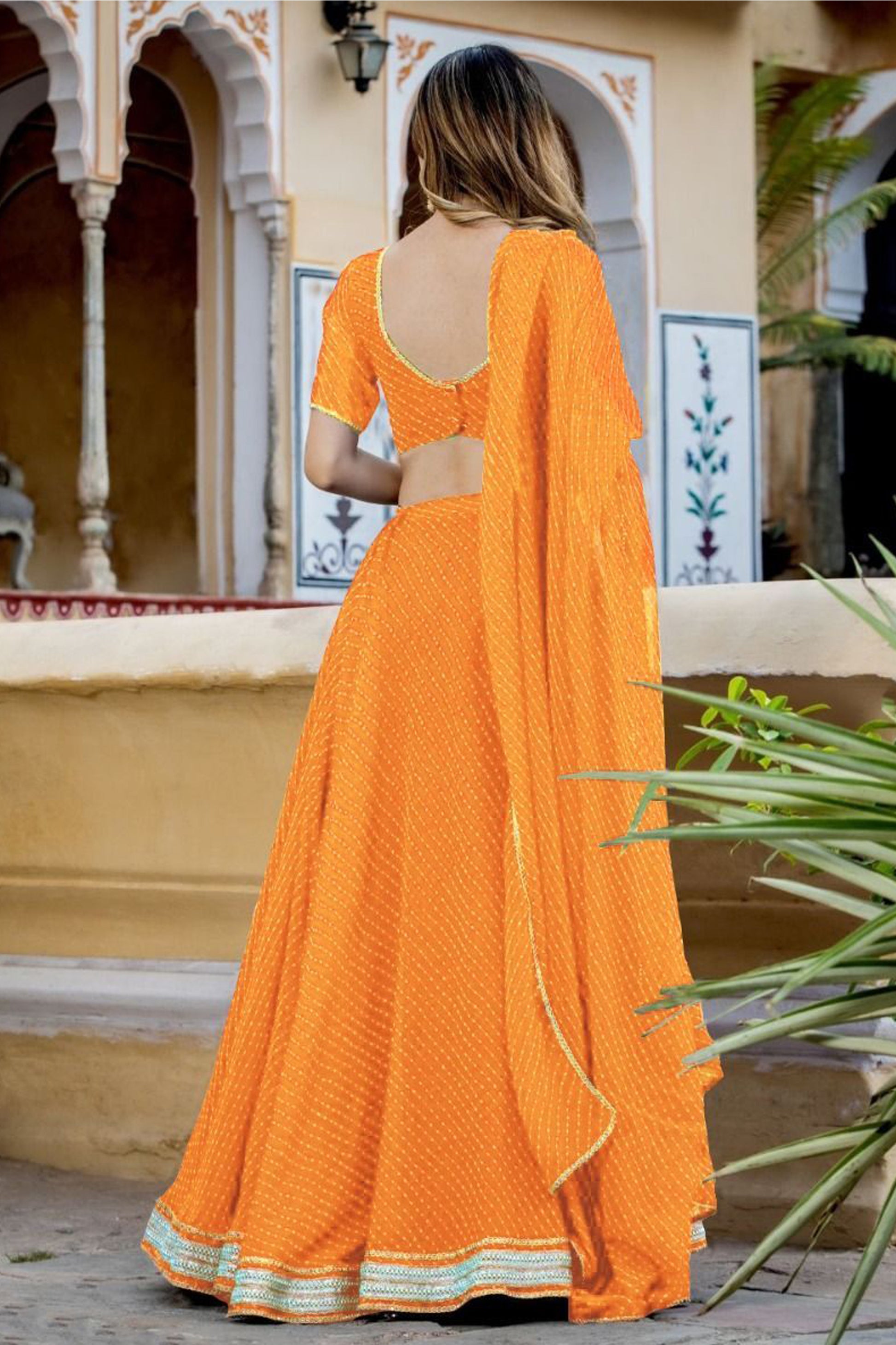Orange lehenga back view with flowing drape
