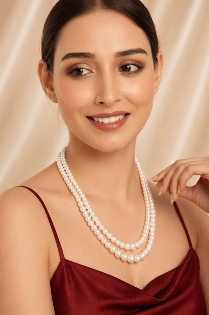 Woman wearing a pearl necklace against a beige background