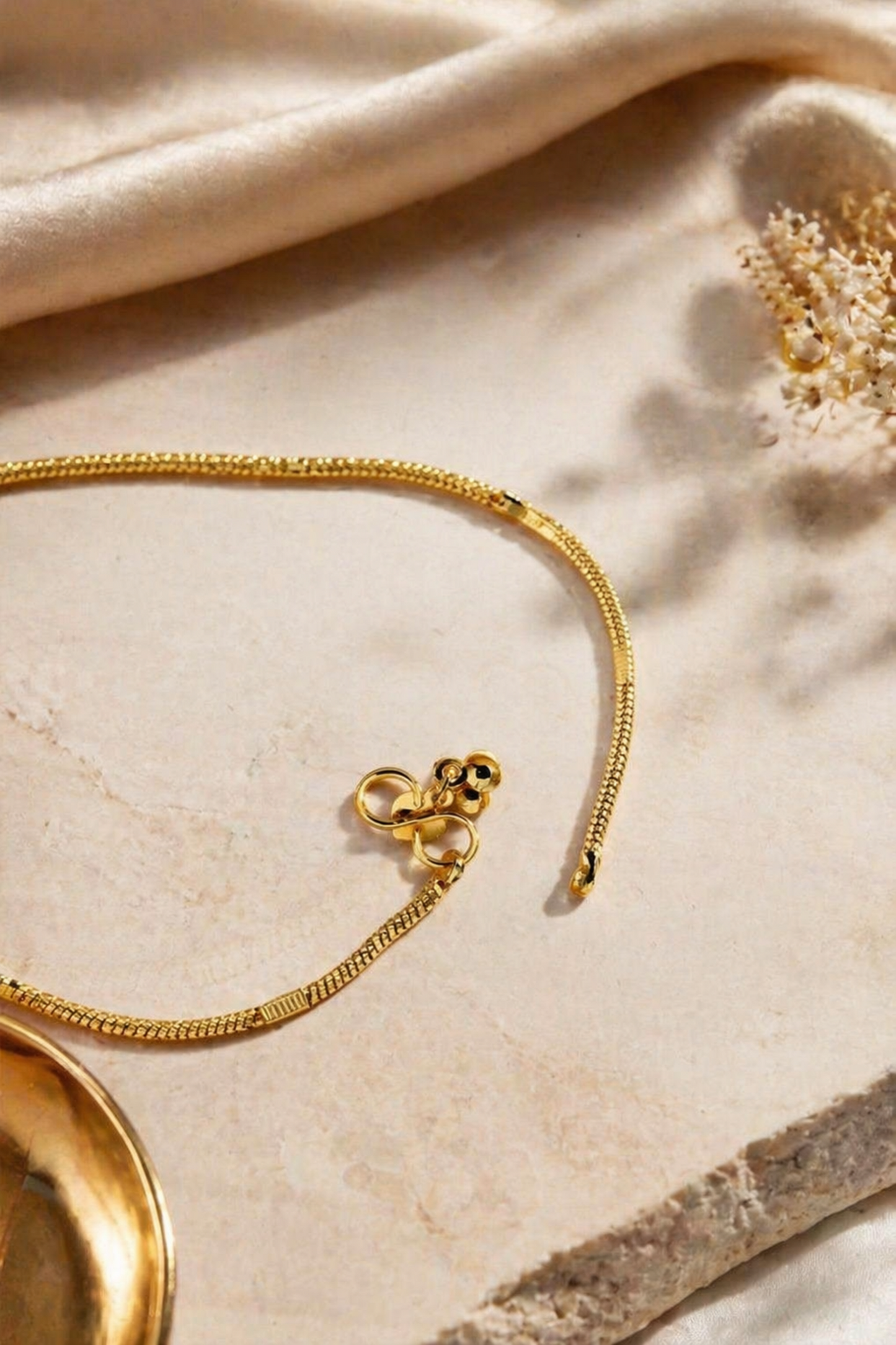 Gold bracelet on a textured beige surface with a subtle focus effect
