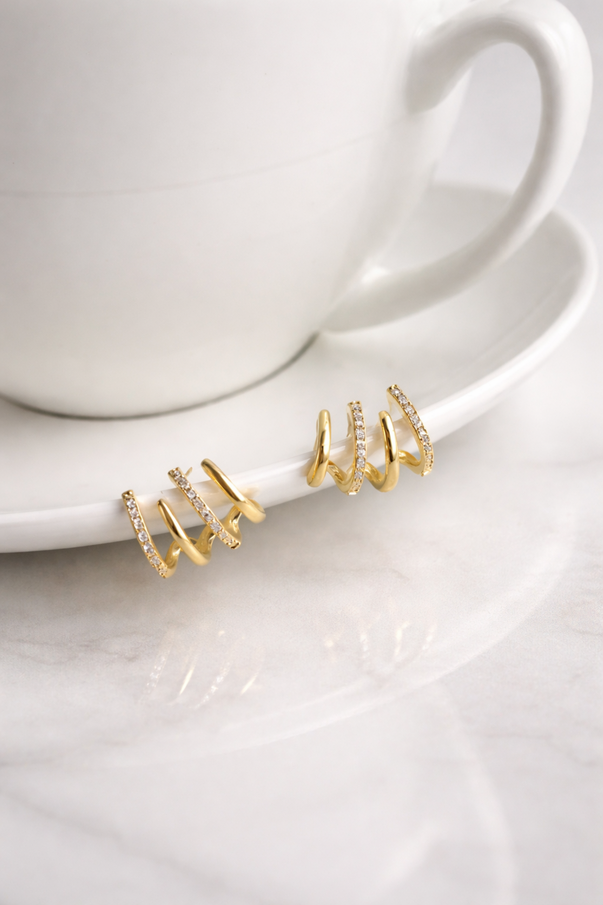 Gold multi hoop ear climber earrings with crystal accents on white cup