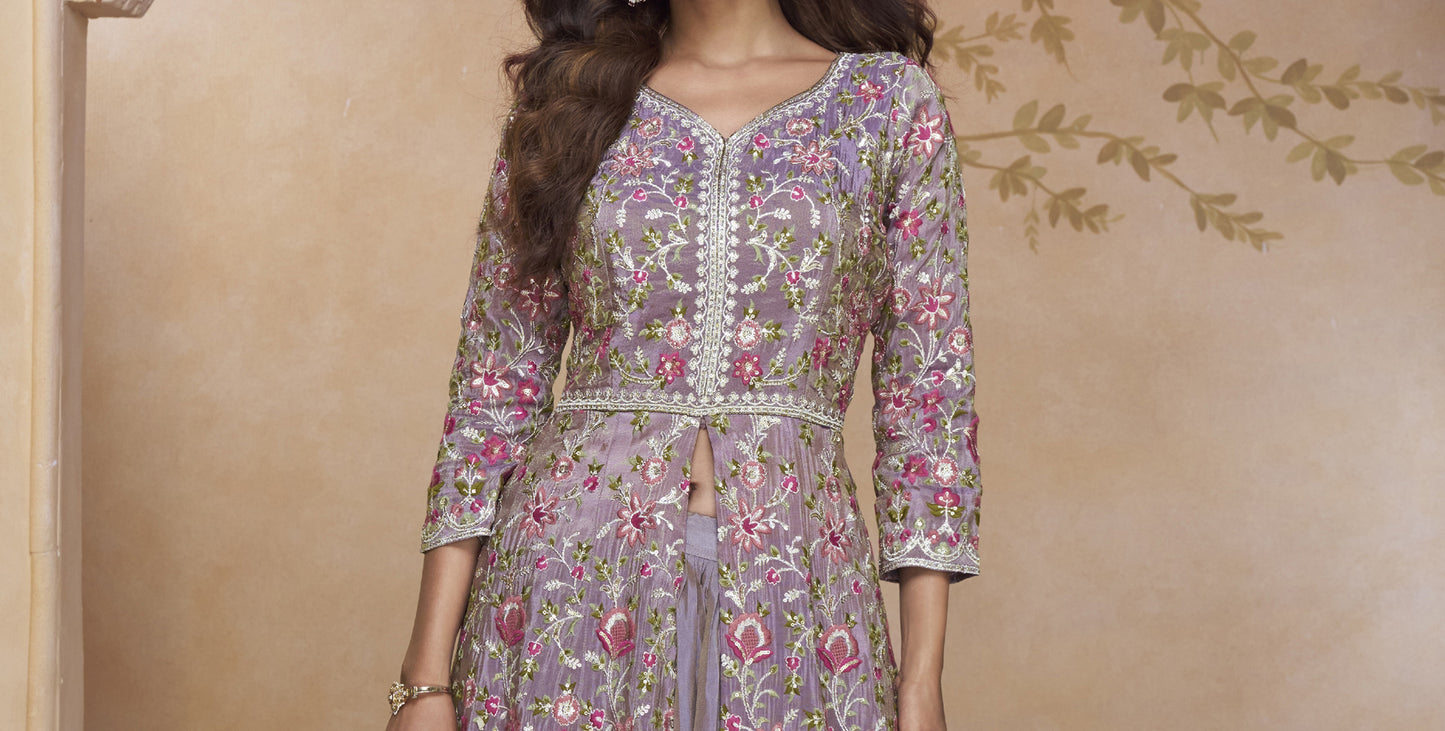 Elegant Mauve-Purple Full-Length Gown with Heavy Ethnic Embroidery Paired with Statement Earrings in a Palace-Themed Setting