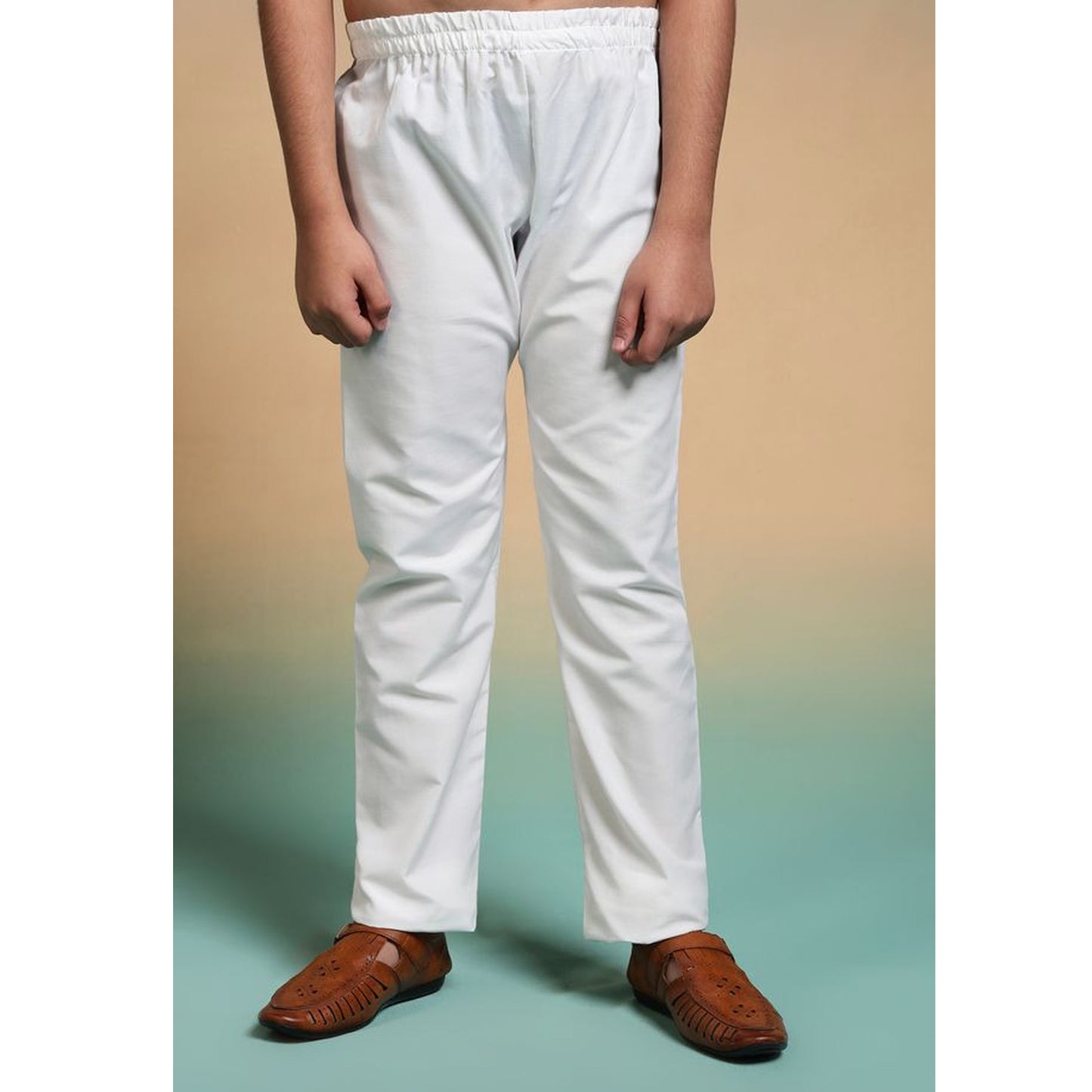 Person wearing white pants and brown shoes on a gradient background