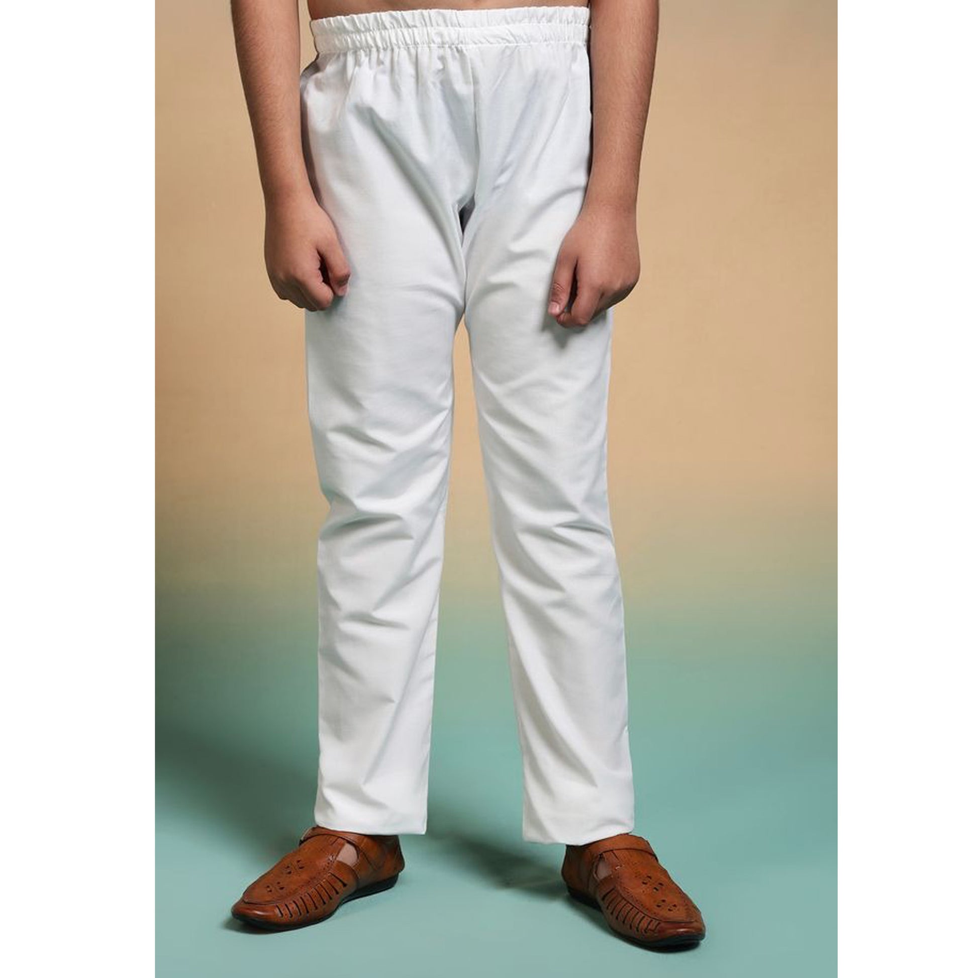 Person wearing white pants and brown shoes on a gradient background