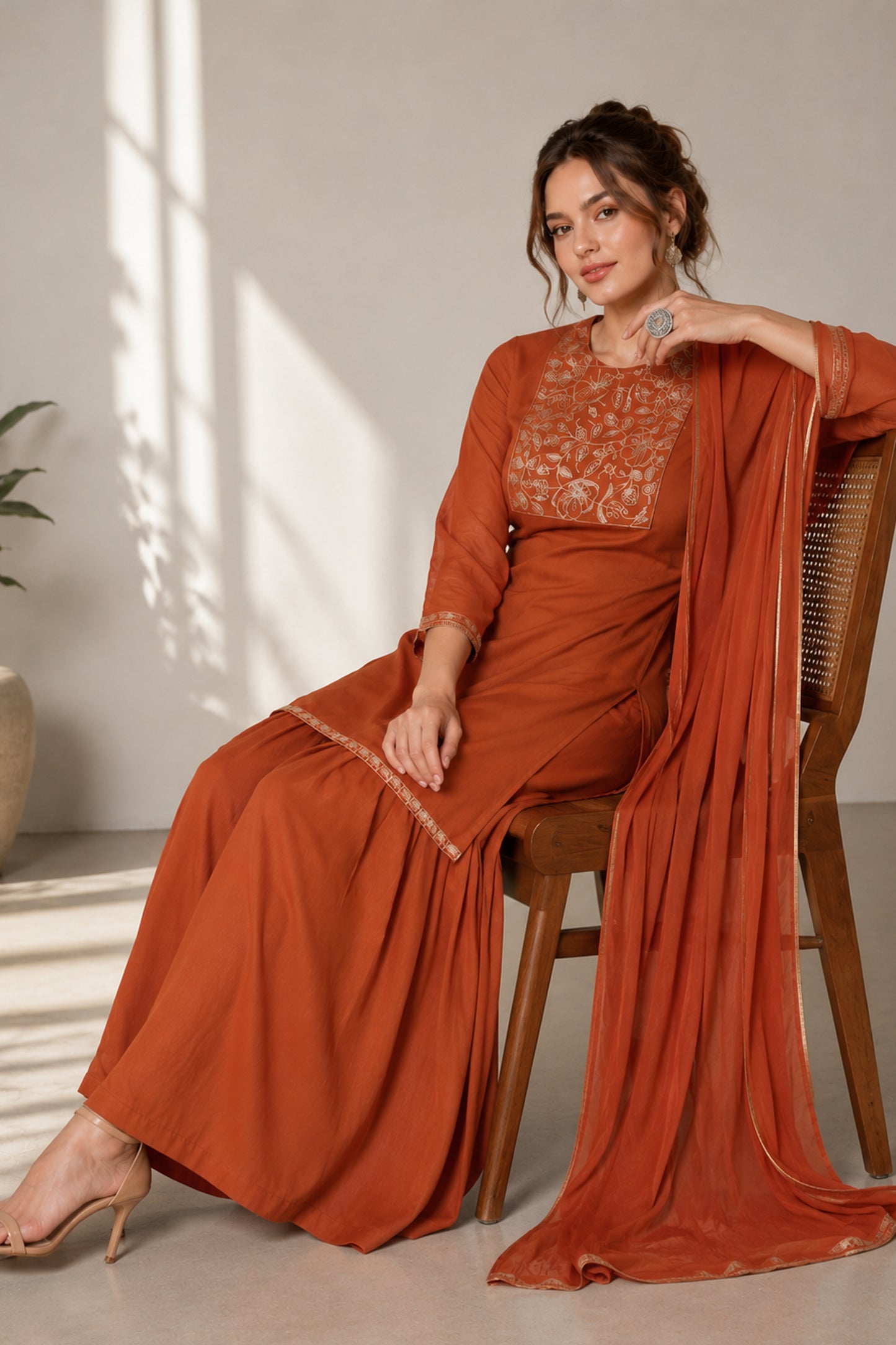 orange sharara suit for women shown in a seated front view