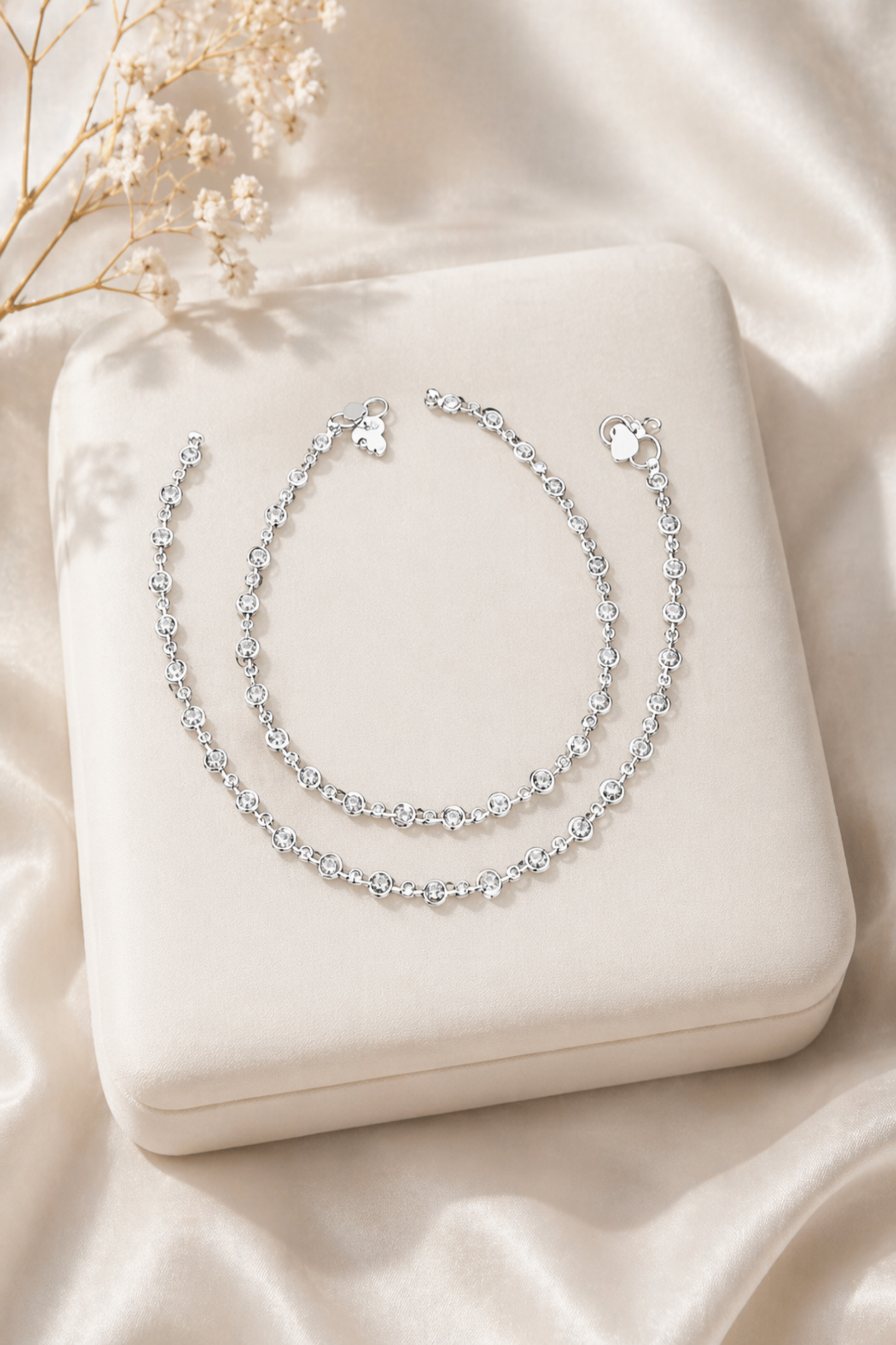 silver anklet with round clear stones on marble surface