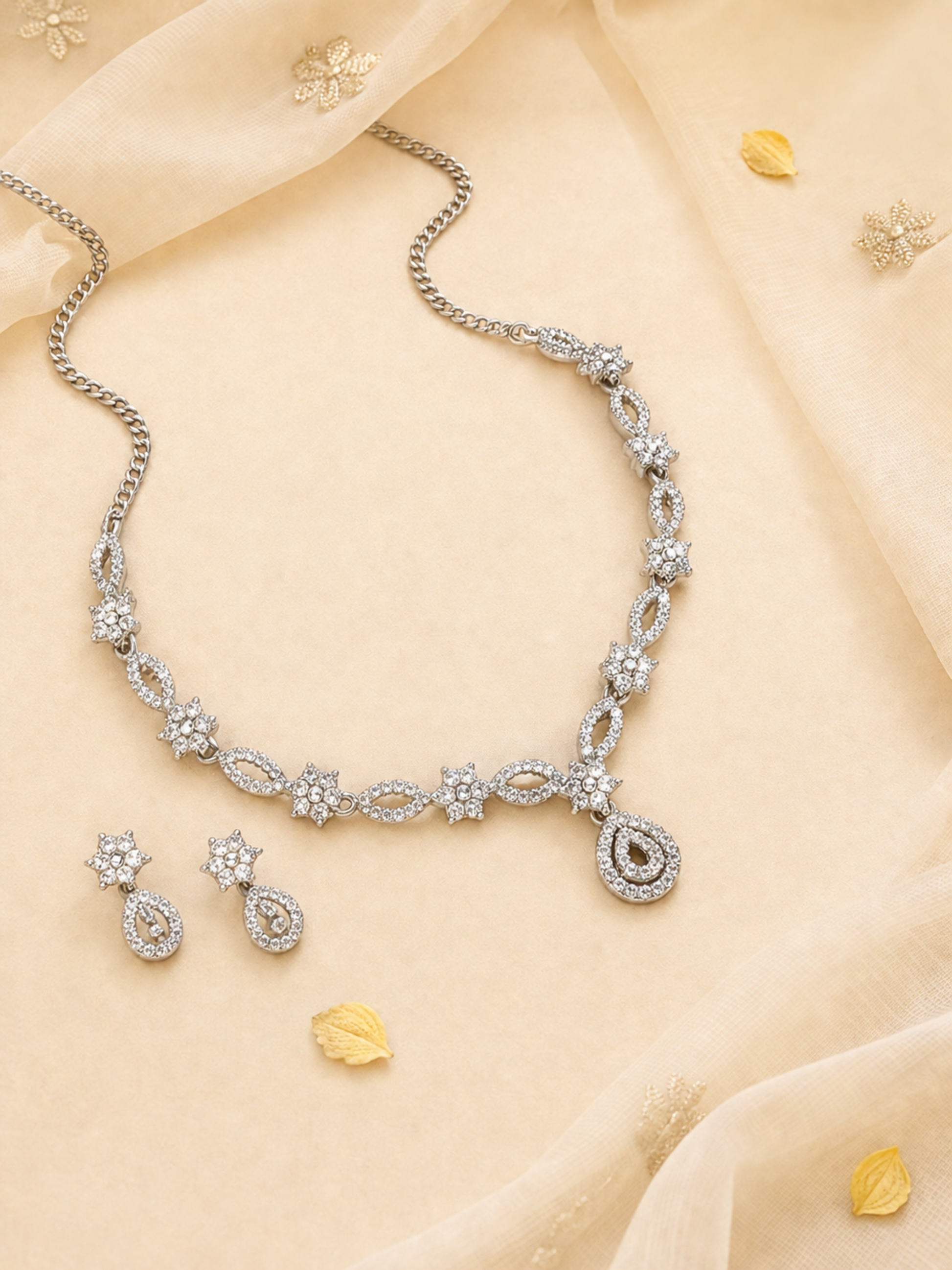Silver teardrop jewelry set styled with floral backdrop