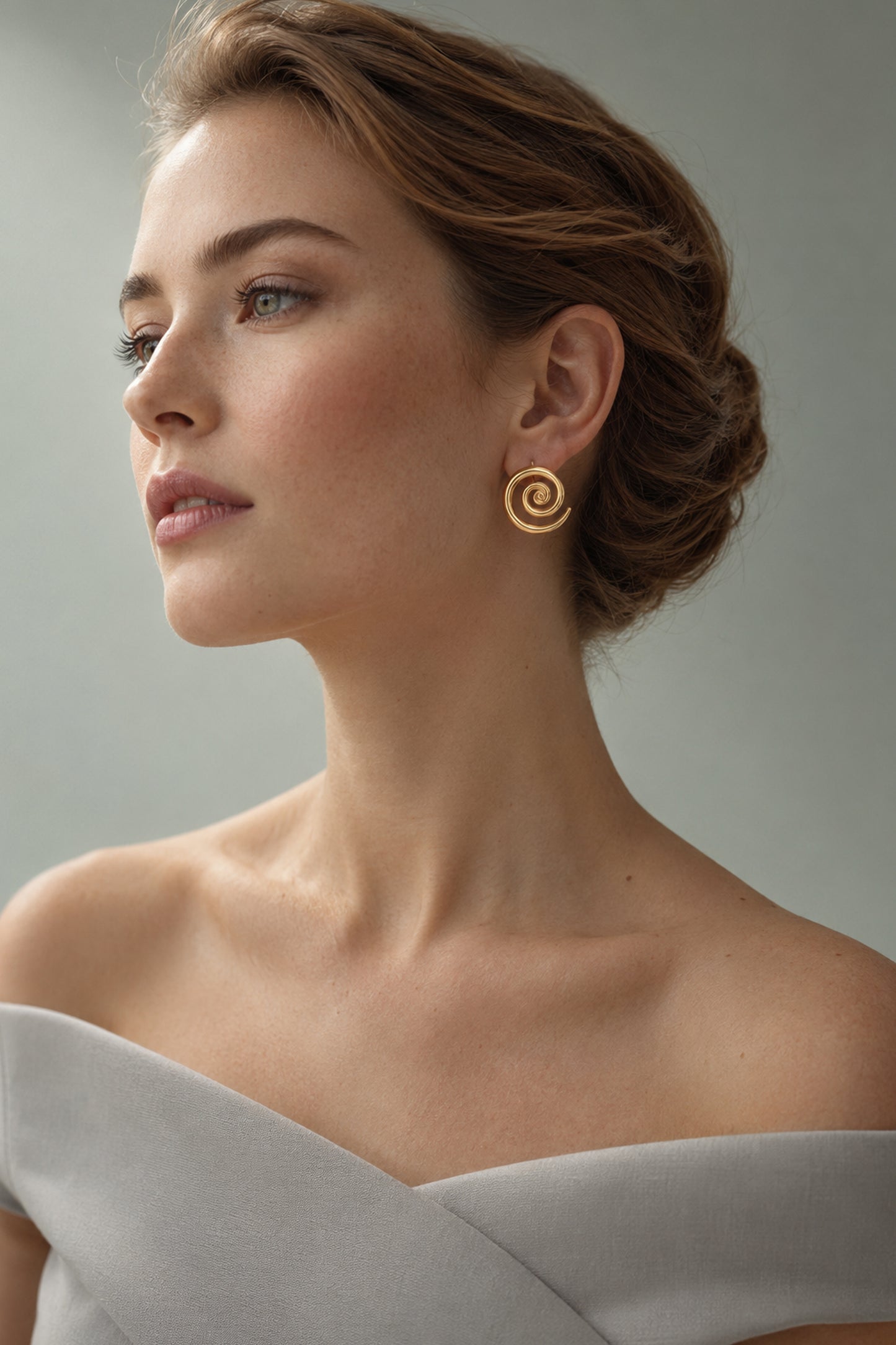 Round spiral earring worn by a model with swept-back hair