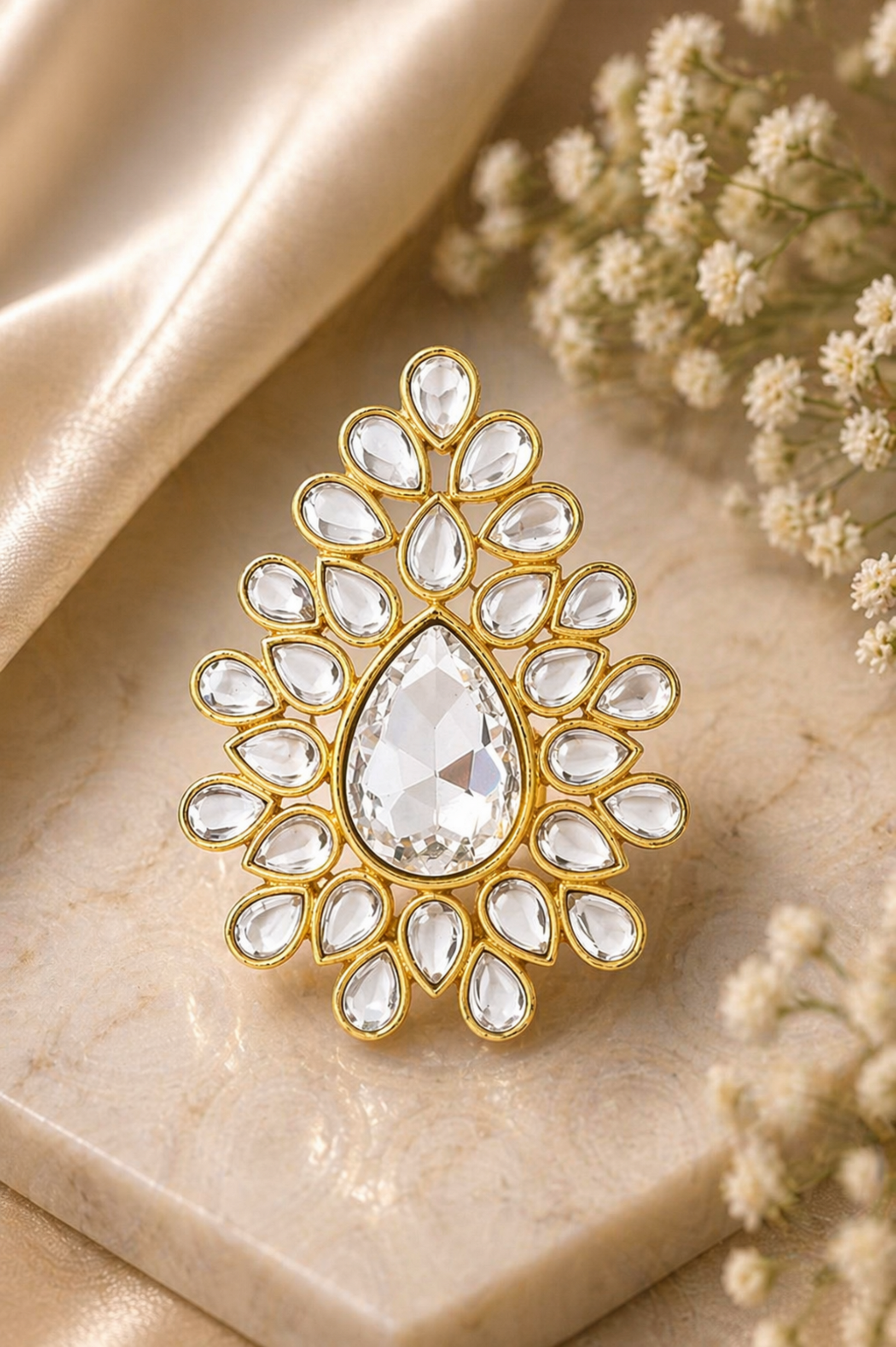Gold and crystal brooch on a marble surface with flowers