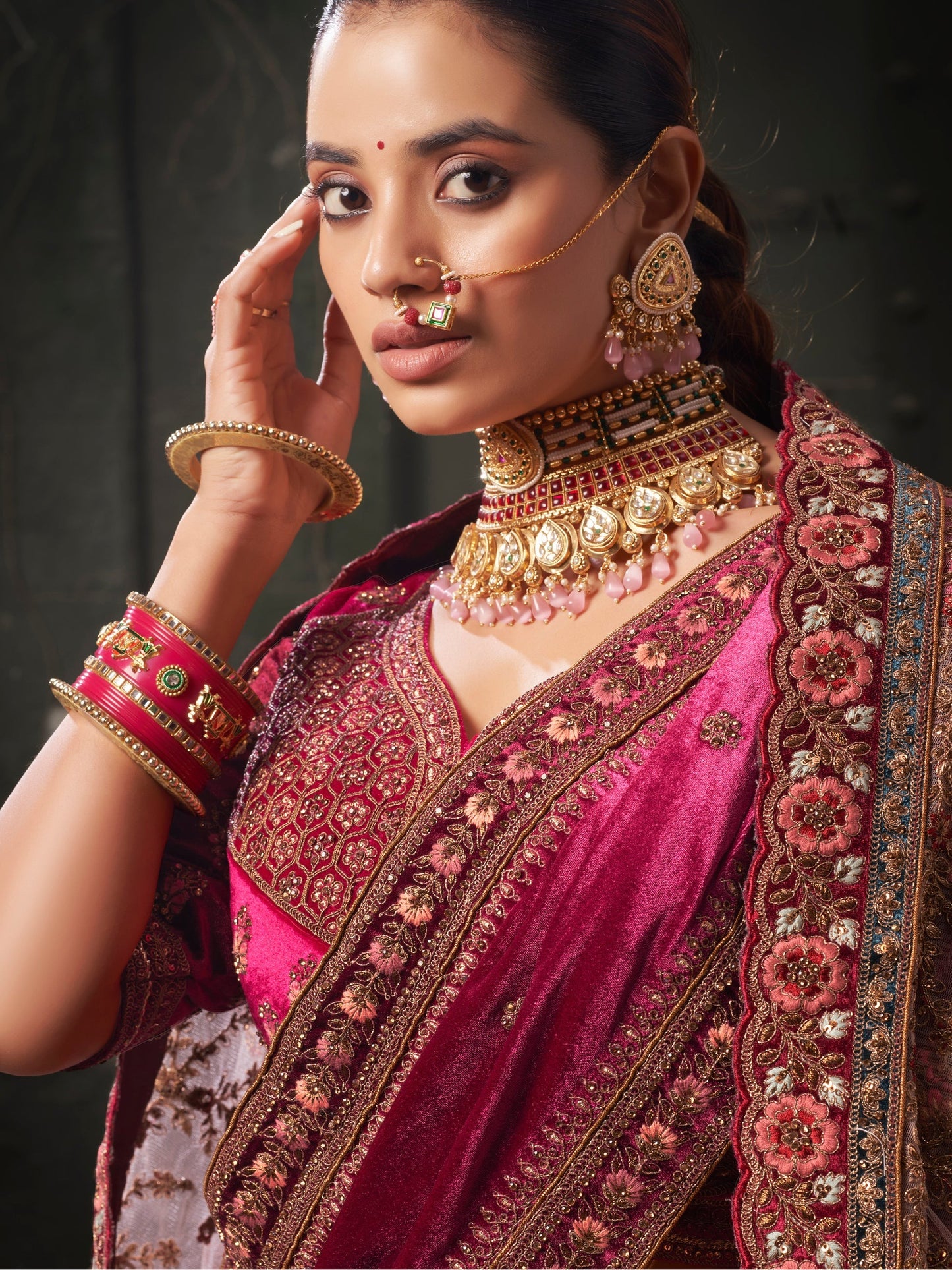 Close-up of thread embroidery on pink velvet lehenga