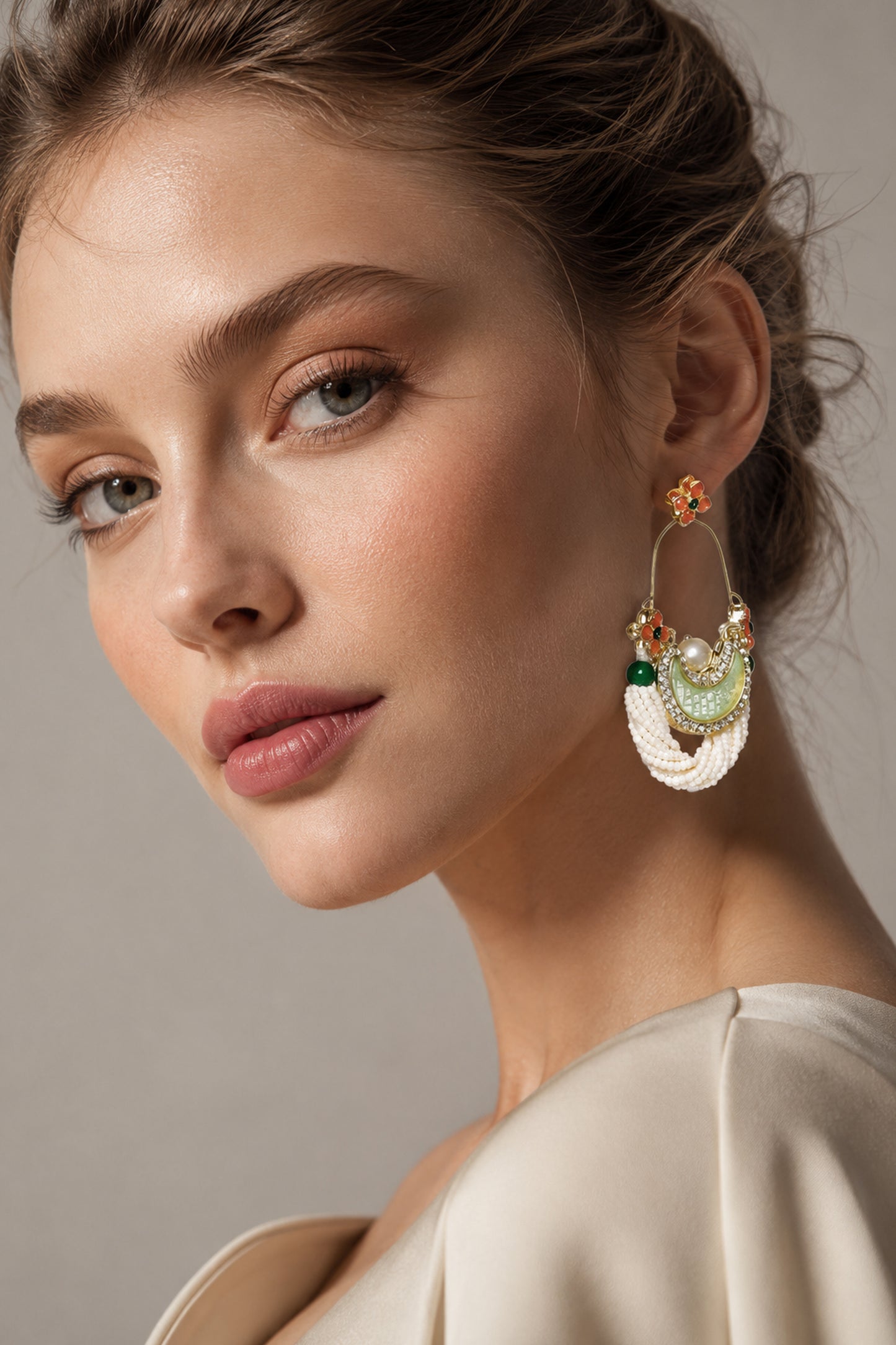 Gold-tone earrings with white bead strands and pale green crescent detail