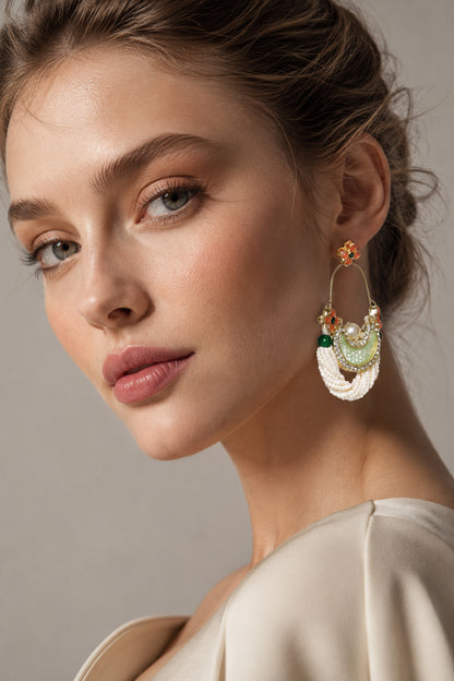 Gold-tone earrings with white bead strands and pale green crescent detail